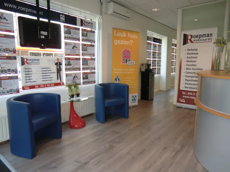 Ontvangstruimte van het kantoor van Roepman Makelaardij met de woningpresentaties in de etalage
